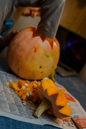 Child carves from a pumpkin. family fun activity. arved pumpkins into jack-o-lanterns for halloween.の写真素材