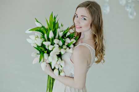 lovely girl hold in her hands bouquet of flowers of tulips. gift to woman for holiday for Women's Day. Happy bride. Valentine's Day. March 8th Beautiful girl smiling.の写真素材
