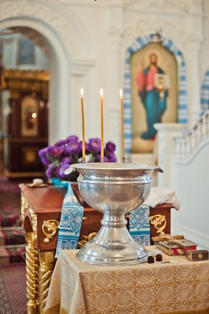 font for the baptism of an infant with burning candles. Interior Of Orthodox Church In Easter. baby christening. Ceremony a in Christian . bathing the into the baptismal font. Soft focusの写真素材