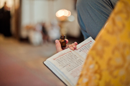 Kiev, Ukraine - september 22, 2018. The priest holds a bottle of chrism, and a book of prayers for christening.の写真素材