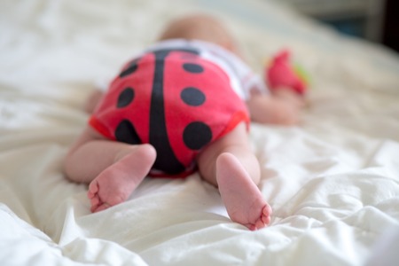 Booty baby in the body in the form of a ladybug. A newborn baby is lying on the belly. Baby is trying to crawl. Baby from the back.の写真素材