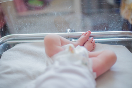 Legs newborn baby lying in couveuse. child just been born and in hospital clinic with mother. Natural childbirth. Cesarean section.の写真素材