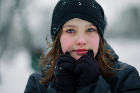 The girl is holding her hands in front of her face. Child with pink cheeks from frost.