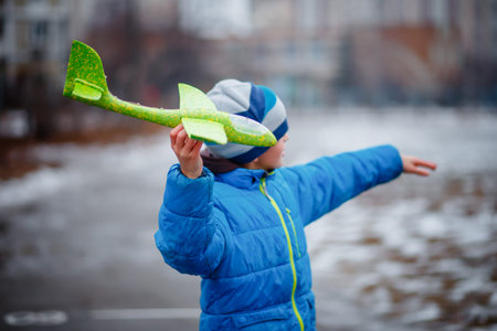 boy launches glider plane green in winter. Active games on air. Airplane flights. Traveling in...