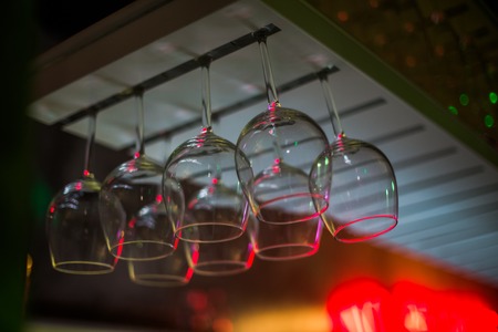 Bocals hanging on the bar. Wine glasses in a restaurant at a party. Light music and laser show in a bar or cafe.の写真素材