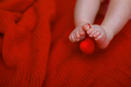 Heart shape on toe of newborn baby. baby lies on red knitted background. Mothers Day. Valentine's Day. best gift to parents.の写真素材