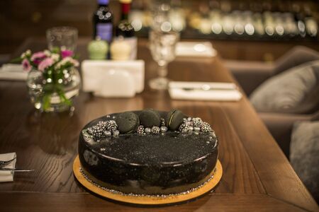 Black chocolate cake on a wooden table. Decorated with chocolate chip cookies birthday cake on a restaurant background.の写真素材