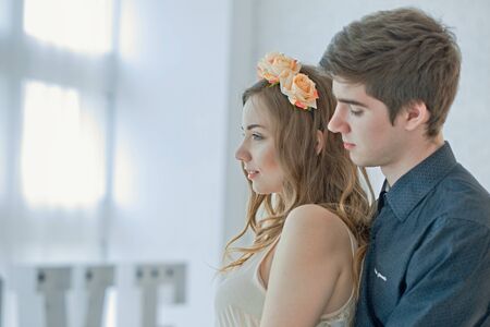 guy hugs girl from behind. couple in love against light big window on sunny day. happy couple celebrates Valentine's Dayの写真素材