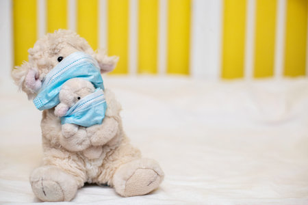 small toy sheep mother with lamb in hands with phonendoscope sit in cot. Toy in protective medical...