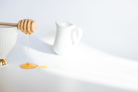 Honey flowing from turfed honey stick. honeys do on white background. Breakfast cream jugの写真素材