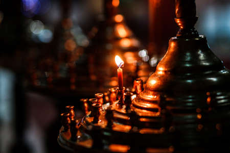 holiday candlelight service or memorial vigil. Red candle in the church. Cathedral, christianity. Bluredの写真素材