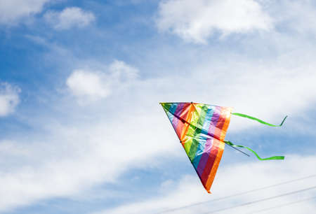 rainbow kite flying in blue sky with clouds in summer with copyspaceの写真素材