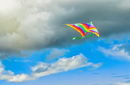 rainbow kite flying in blue sky with clouds in summer with copyspace