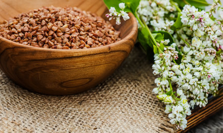 large bouquet of flowering buckwheat with green fruits on wooden cutting board. Vintage table with ecological wooden plates.の写真素材