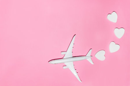Happy Valentine's Day. White passenger plane with hearts on pink background. Flat lay vacation planing and traveling holiday. Holiday travel concept. Top viewの写真素材