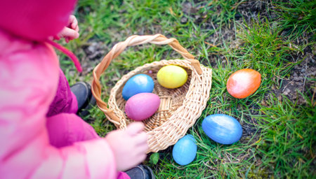 child collects colorful Easter eggs in basket. Easter egg hunt concept.の写真素材