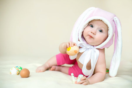 Easter concept. little girl in Rabbit hat. child holds an Easter egg. Funny toddler lies and looks...
