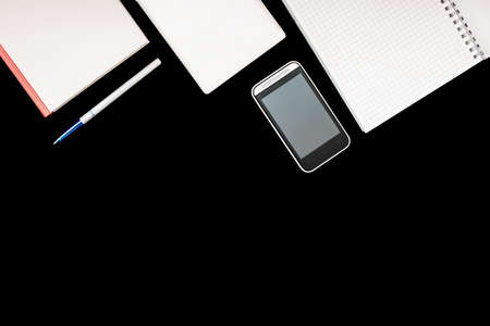 notebook on rings, mobile phone, pen, book and tablet on black background. Set for online training and Education and distance work. Flat lay. Top view.の写真素材