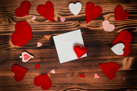 Mother's Day handmade Craft gift. Hand-carved red hearts from felt. Making craft valentine. Preparations for Valentine's Day: notebook for congratulation or sweet notes on wooden tableの写真素材