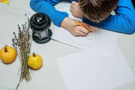 Boy drawing a face on a large halloween pumpkin. Halloween holiday and family lifestyle background.の写真素材