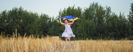 Banner for Ukraines Independence Day. flag of Ukraine in hands of child. schoolgirl runs on wheat...