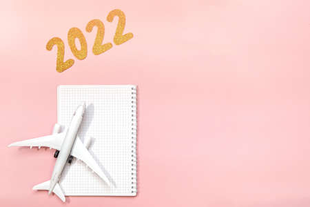 coming 2022 text on pink background. Flat lay design of work desk. with Planning or notebook. New Year for independent travelers and travel agents. place for text. Copy spaceの写真素材