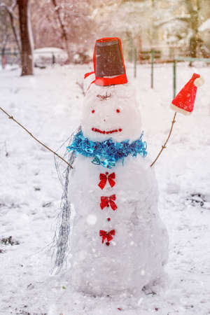 Happy snowman with smile against the backdrop of winter landscape during snowfallの写真素材