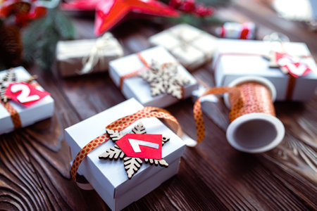 Gift box for the advent calendar. Making a calendar to prepare for Christmas. Decorating gifts. Tag with the number 24, the day before Christmas on a wooden tableの写真素材
