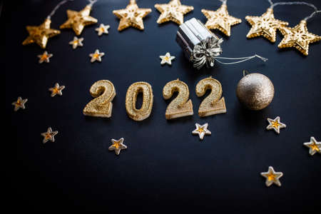 Happy New Year 2022. Holiday background with golden Christmas decorations. 2022 numbers with gold jewelry balls and garland in form of stars.の写真素材