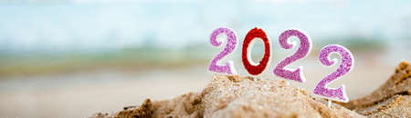 Figures 2022 against background of coastal waves by ocean or sea with caramel cane. Travel during quarantine on New Year's Eve. Celebrating the 2021 departure on beach bannerの写真素材