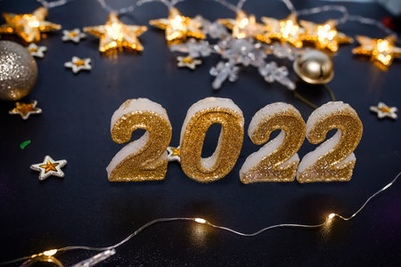 Happy New Year 2022. Holiday background with golden Christmas decorations. 2022 numbers with gold...
