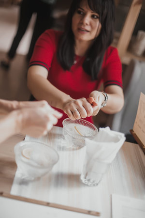 Girl washes her hands in a special dish slop-basin with lemon. Woman washing hands in lime water in...