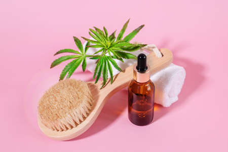Black glass unbranded bottles of cosmetic oil and cannabis essential oil and a wooden facial cleansing brush with natural bristles. Natural skin care and aromatherapy .Spa, wellness, massage conceptの写真素材
