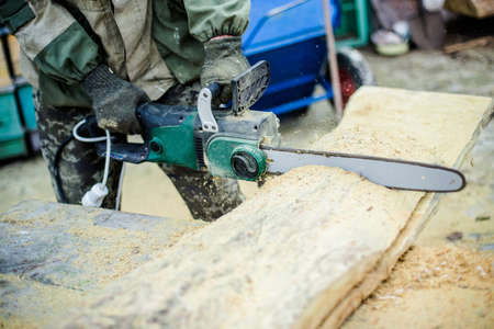 Saws in hand fitter. The man saws a thick piece of wood. From thの写真素材