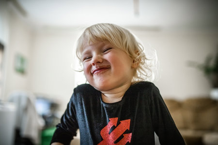 A funny girl writhes a face against the background of a room in a Halloween costume. Chocolate-stained face of a satisfied childの写真素材