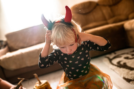 A girl with devil's horns at a Halloween party at home. The child dressed up for all saints' day