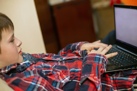 boy in plaid shirt does lessons on laptop. child learn remotely during quarantine of coronavirus....