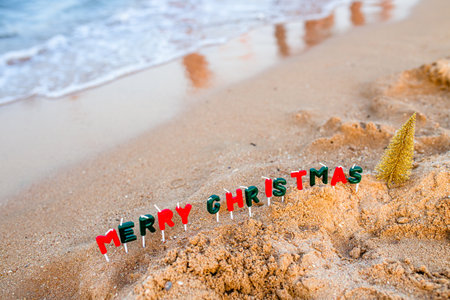 Vacation by the sea. Celebration of the traditional December holiday near the ocean. The text of a Merry Christmas made of candles next to the foaming wave.の写真素材
