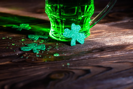 clover leaves with splashes of cold beer on a wooden table. A glass of green traditional beer on St. Patrick's Day in an Irish pubの写真素材