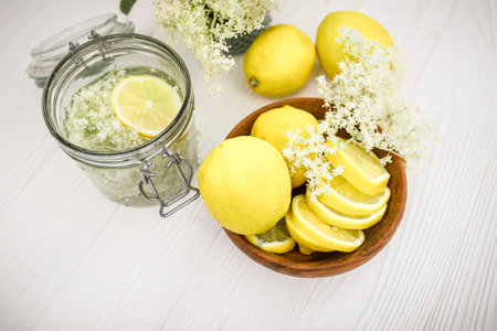 Top view of lemon slices and a glass of refreshing drink with elder syrup in summer on the village table. Homemade lemonade liqueur from elderberry flowers used in homeopathy and alternative medicineの写真素材