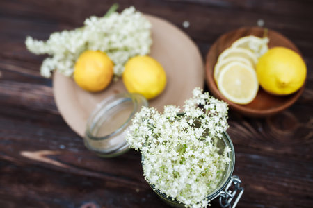 Top view of the ingredients for a refreshing summer drink made from elderberry syrup and lemons. Freshly cut elderberry flowers and sliced lemons on a vintage rustic table.の写真素材