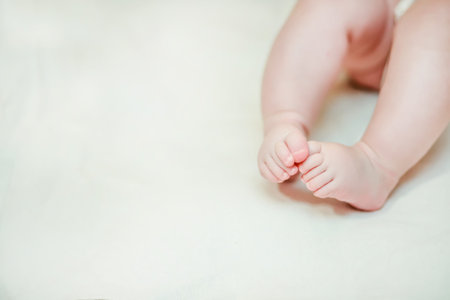 The legs of the baby 2-5 months folded her fingers together. tiny legs of a child lying on his back....