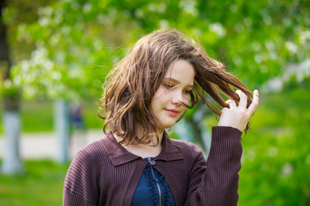 Beautiful girl among cherry flowers in spring. Portrait of a girl with brown hair and green eyes.の写真素材