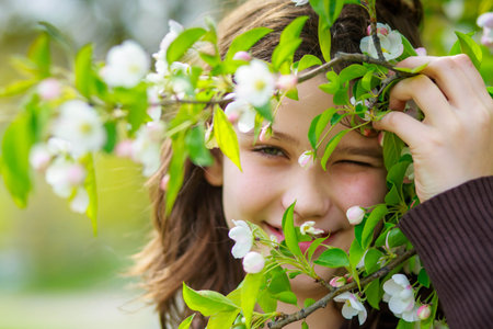 Beautiful girl among cherry flowers in spring. Portrait of a girl with brown hair and green eyes.