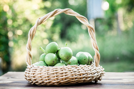 green nuts Walnuts in a wicker basket. Ingredient collection for healthy food. Old vintage table and whole unripe walnut fruitの写真素材
