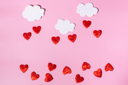 Paper white clouds with rain of red hearts. Conceptual background for Valentine's Day or Women's...