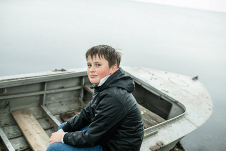 Portrait of a boy sitting in a boat on the lake.の写真素材