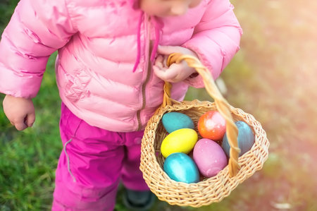 child collects colorful Easter eggs in basket. Easter egg hunt concept.
