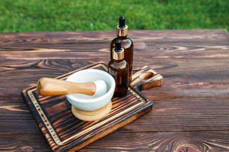 A set of pharmaceft manufacturing medicines from ecologically pure herbs. Ceramic mortar on a wooden cutting board and cosmetic bottles.の写真素材