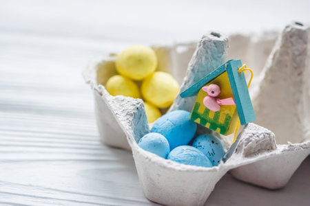 A bunch of yellow and blue eggs in egg carton. near the house with a bird. The concept of an abandoned home of Ukraine for the Easter holidayの写真素材